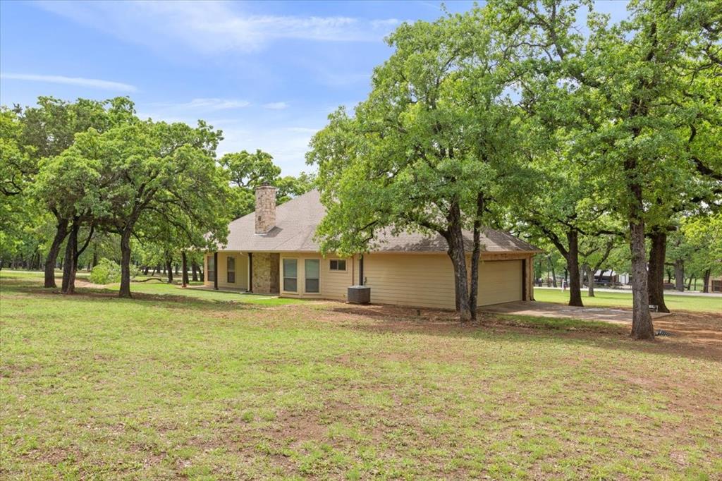 140 Oak Ridge Loop Whitney, TX 76692 - Photo 37 of 40 The property features an expansive lawn and numerous mature trees, providing natural shade and a serene outdoor environment