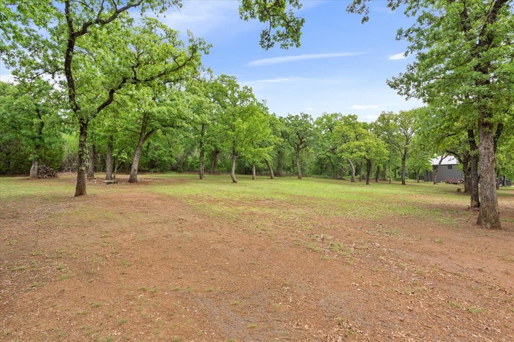 140 Oak Ridge Loop Whitney, TX 76692 - Photo 38 of 40 The property features an expansive outdoor area with a mix of grass and natural ground, surrounded by numerous mature trees