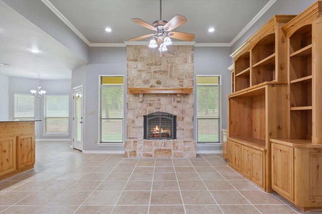 140 Oak Ridge Loop Whitney, TX 76692 - Photo 8 of 40 This living area features tile flooring, a stone fireplace with a wooden mantel, and custom wooden built-in shelving
