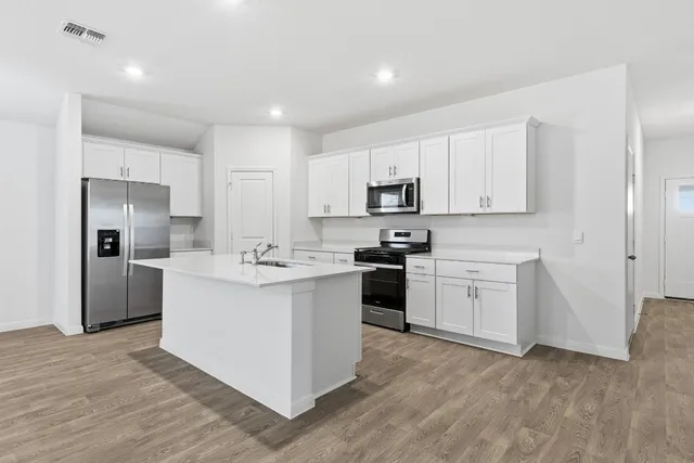 a kitchen with white cabinets appliances and sink
