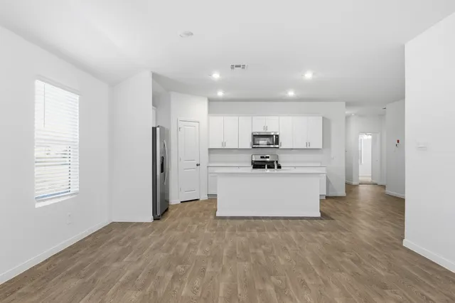 a view of a kitchen with refrigerator microwave and wooden floor