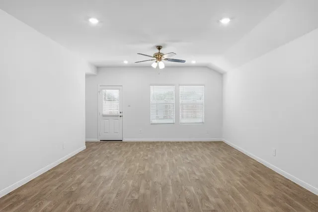 an empty room with chandelier fan and windows