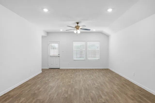 an empty room with chandelier fan and windows