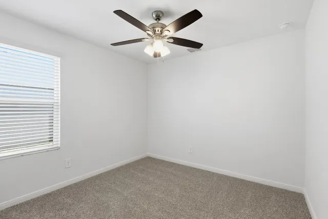 an empty room with a window and a ceiling fan