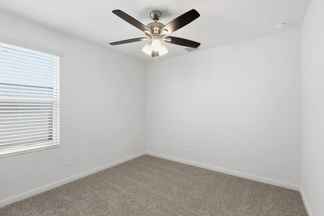 an empty room with a window and a ceiling fan