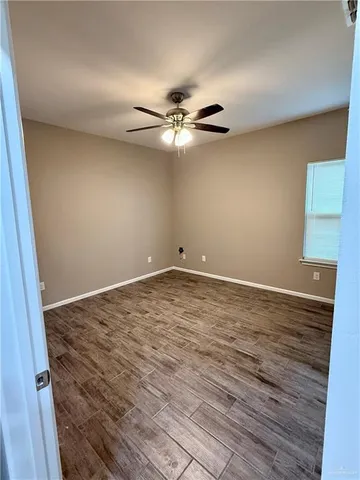 a view of a room with wooden floor and a ceiling fan