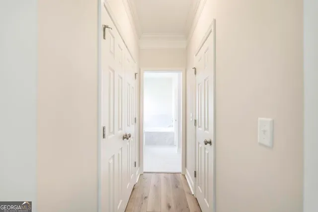 a view of a hallway with wooden floor and a bathroom