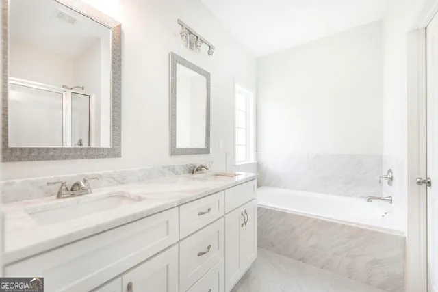 a bathroom with a granite countertop sink a mirror a bathtub and next to a window