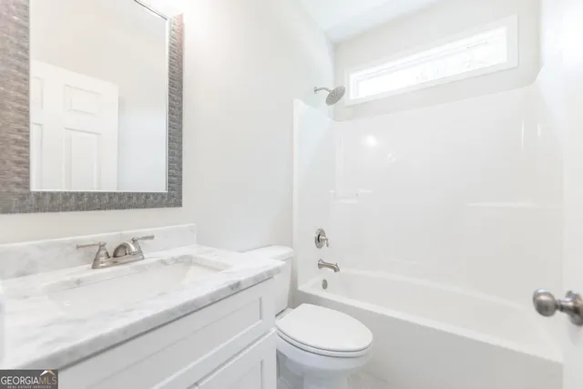 a bathroom with a granite countertop sink a toilet and shower