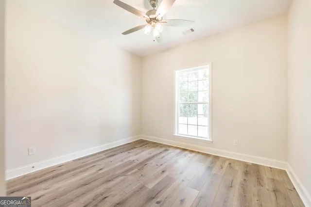 an empty room with wooden floor fan and windows