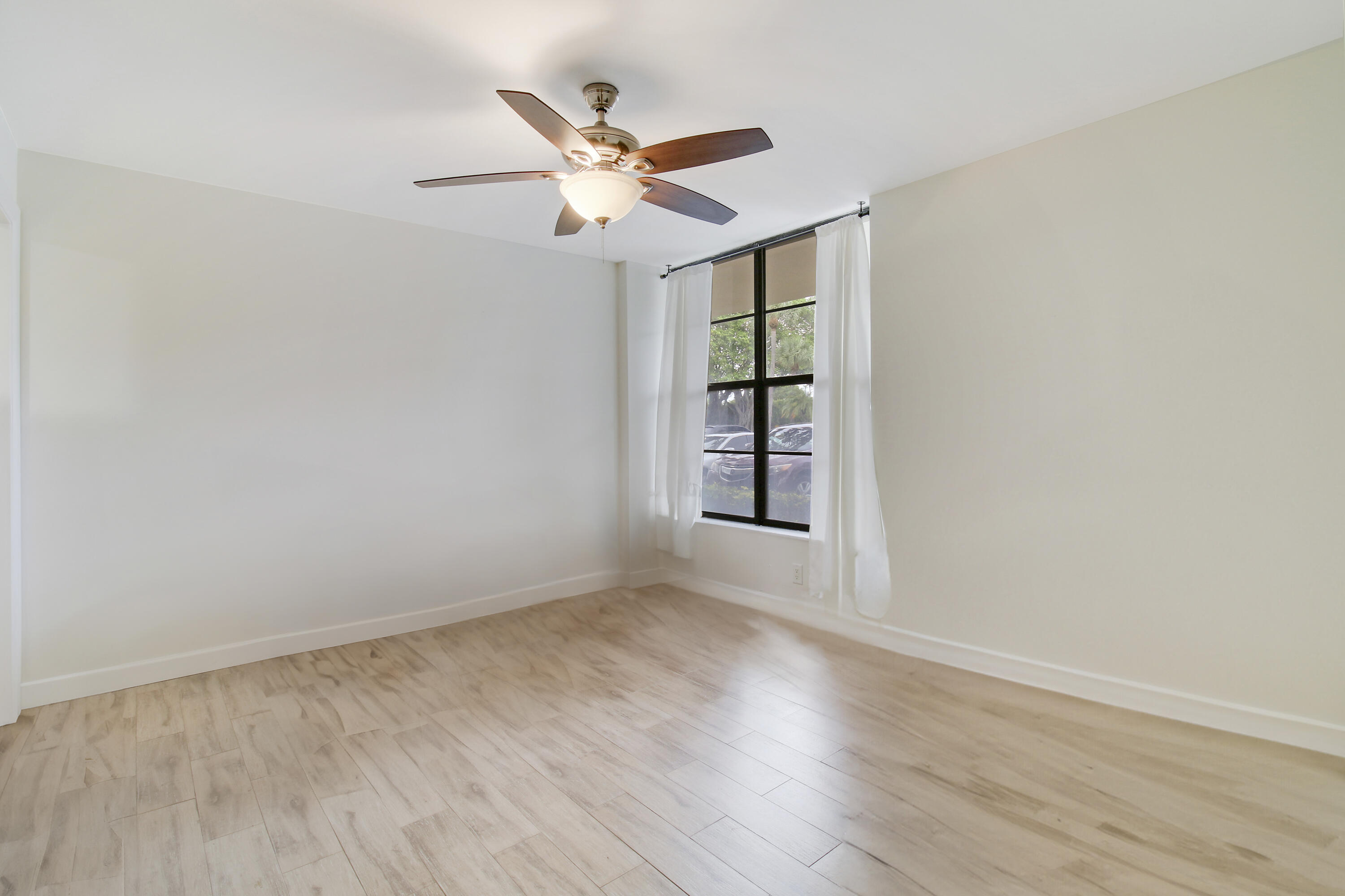 9 Royal Palm Way, Unit 105 Boca Raton, FL 33432 - Photo 15 of 26 an empty room with wooden floor fan and windows