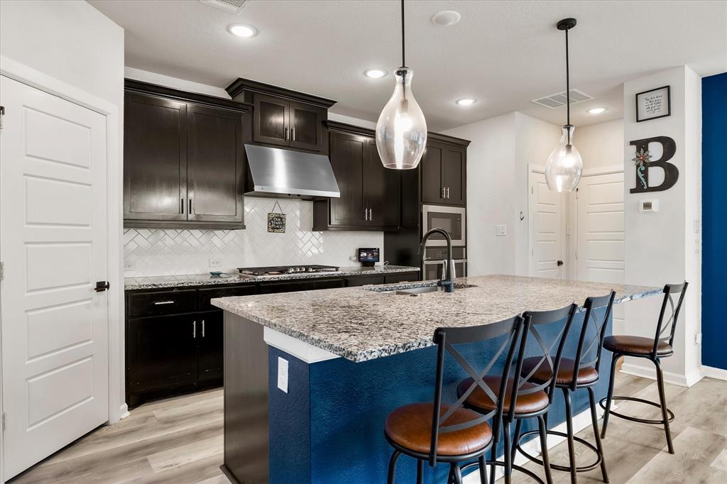 9224 Lamar Street Rowlett, TX 75089 - Photo 6 of 27 Kitchen featuring a spacious island with a granite-style countertop, dark cabinetry, and wood-finish flooring