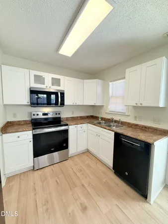 a kitchen with granite countertop a stove top oven and cabinets