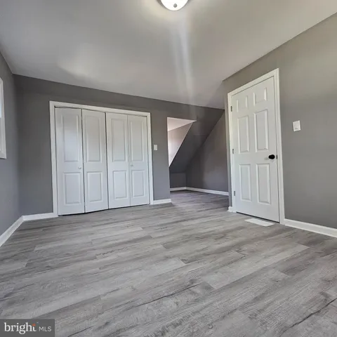 a view of an empty room with wooden floor and closet