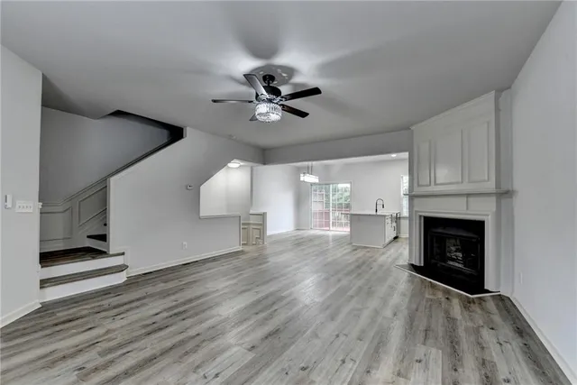 a view of a livingroom with a fireplace a ceiling fan and wooden floor
