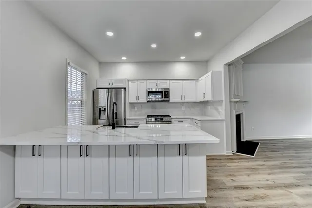 a large white kitchen with kitchen island a sink stainless steel appliances and cabinets