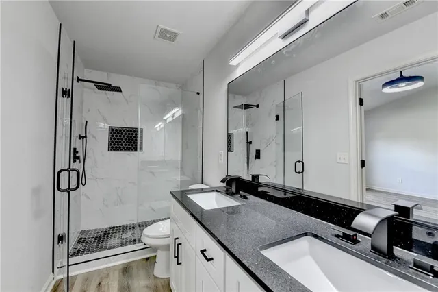 a bathroom with a granite countertop sink a toilet a mirror and shower