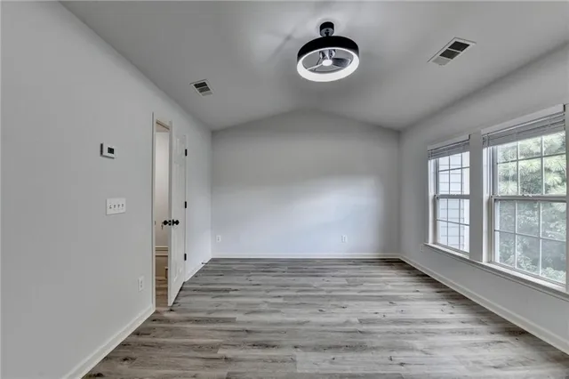 an empty room with wooden floor and windows