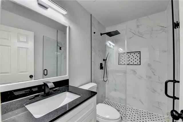 a bathroom with a granite countertop sink a toilet and shower