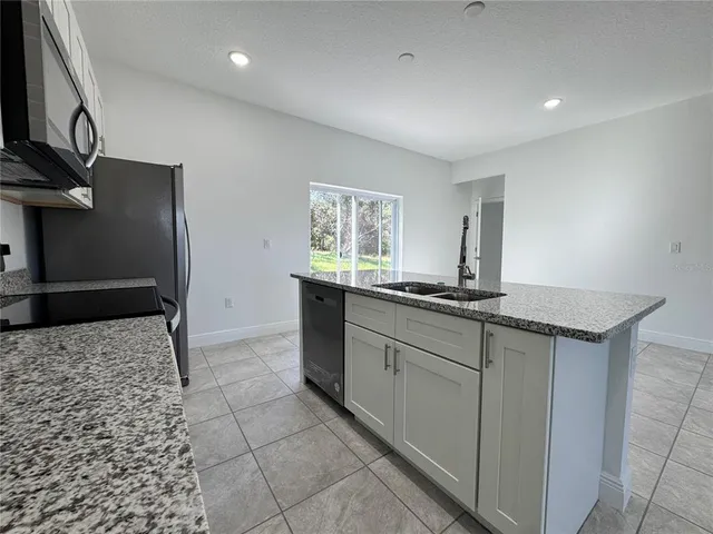 a kitchen with stainless steel appliances granite countertop a sink and a refrigerator