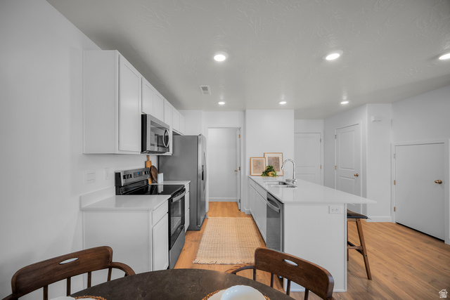 2202 Wolverine Way, Unit 2529 Washington, UT 84780 - Photo 6 of 27 Open-concept kitchen featuring white cabinetry, stainless steel appliances, white countertops, and wood-finish flooring