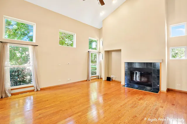 an empty room with windows and fireplace