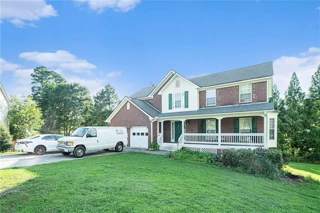a white house with a big yard and large trees