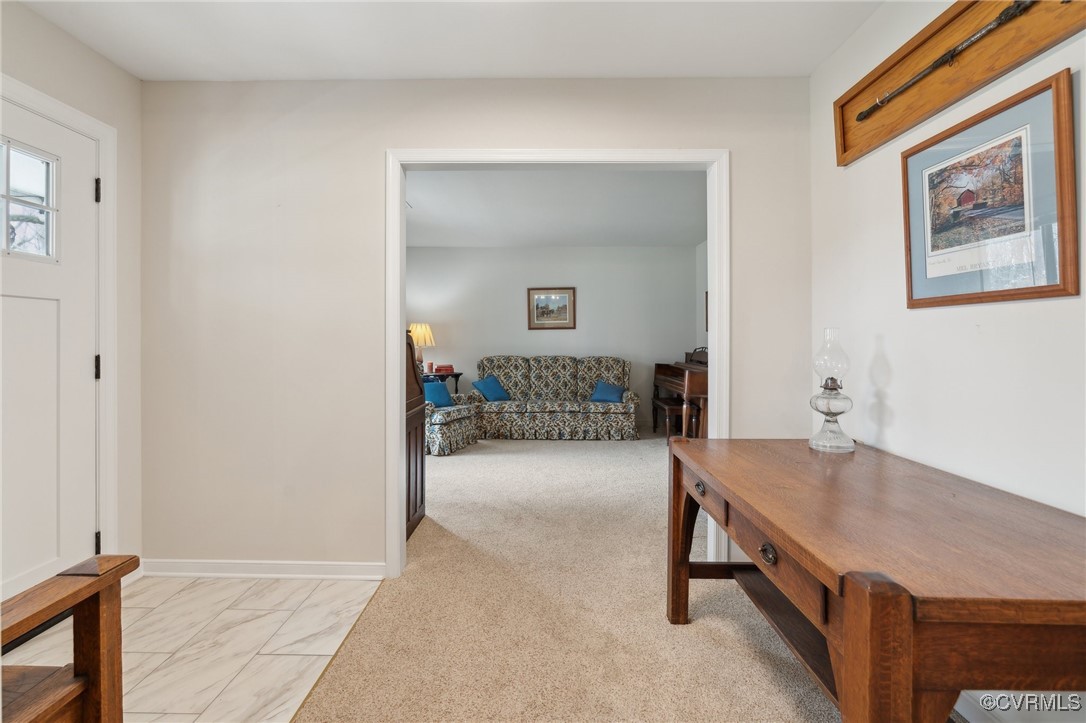 Foyer featuring light colored carpet and baseboard