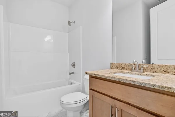 a bathroom with a granite countertop sink toilet mirror vanity and bathtub
