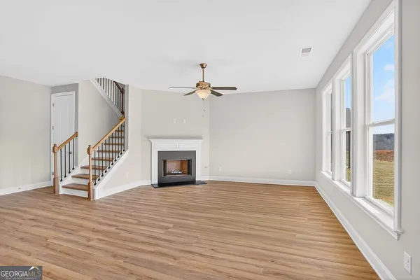 a view of an empty room with wooden floor fireplace and a window