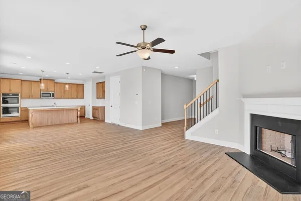 a view of a kitchen and an empty room with wooden floor a fireplace
