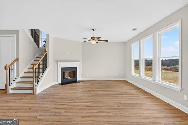 a view of an empty room with wooden floor fireplace and a window