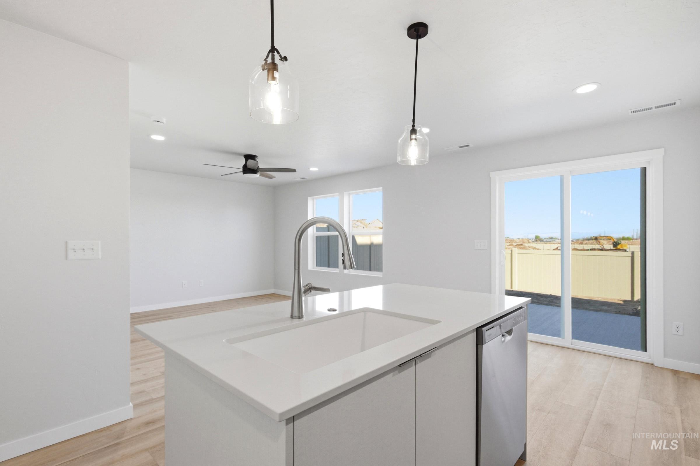 10800 Rutland Street Caldwell, ID 83605 - Photo 5 of 21 Kitchen island featuring a built-in sink with a gooseneck faucet, integrated dishwasher, and pendant lighting
