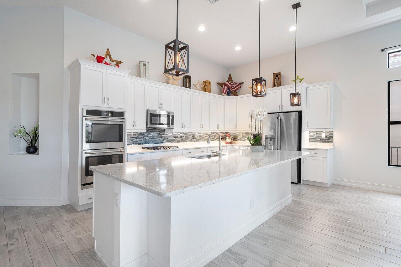 11856 Leon Circle Parkland, FL 33076 - Photo 5 of 43 a large kitchen with stainless steel appliances kitchen island granite countertop a refrigerator a oven and white cabinets with wooden floor