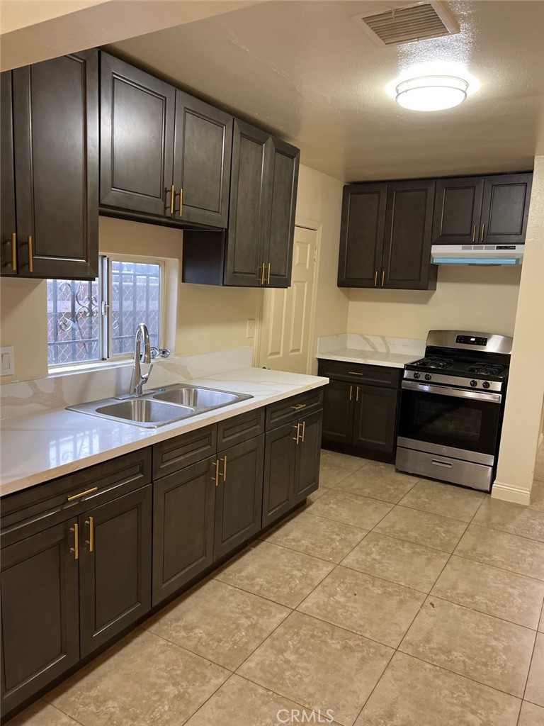 10529 Grape Street Los Angeles, CA 90002 - Photo 6 of 12 a kitchen with stainless steel appliances granite countertop wooden cabinets a sink and dishwasher