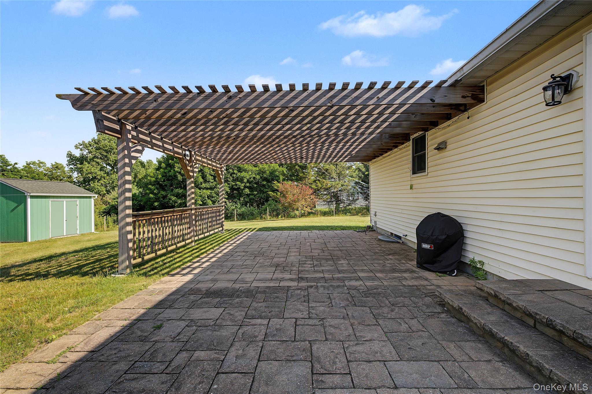318 Cornwall Hill Road Patterson, NY 12563 - Photo 28 of 38 Expansive paver patio featuring a wooden pergola and a wood-slat railing