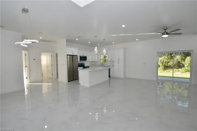 a kitchen that has a refrigerator a sink and white cabinets