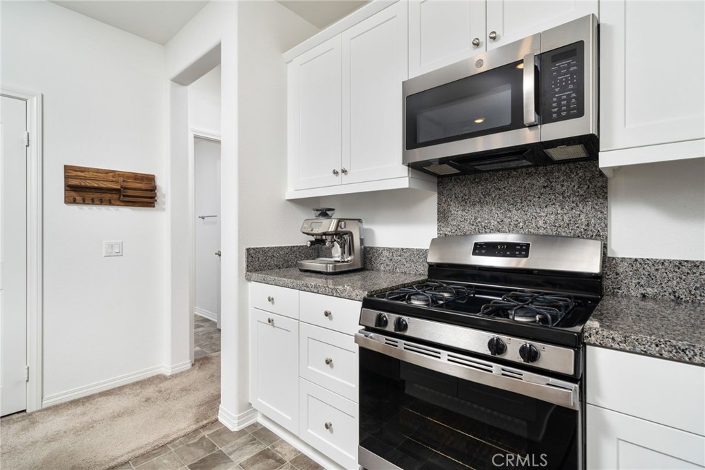 16502 Casa Grande Avenue, Unit 102 Fontana, CA 92336 - Photo 11 of 41 a kitchen with stainless steel appliances granite countertop white cabinets and black stove top oven with granite countertops