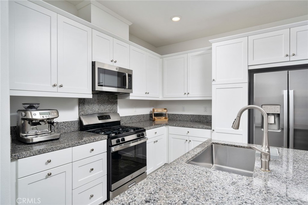 16502 Casa Grande Avenue, Unit 102 Fontana, CA 92336 - Photo 8 of 41 a kitchen with granite countertop white cabinets and stainless steel appliances