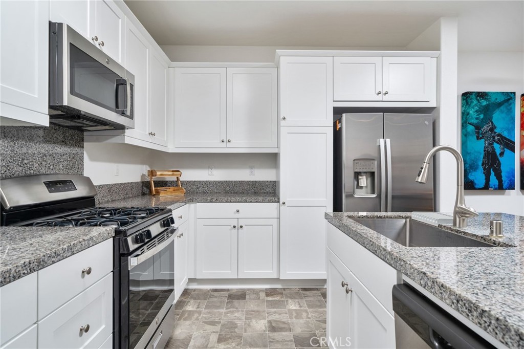 16502 Casa Grande Avenue, Unit 102 Fontana, CA 92336 - Photo 9 of 41 a kitchen with granite countertop a sink stainless steel appliances and white cabinets