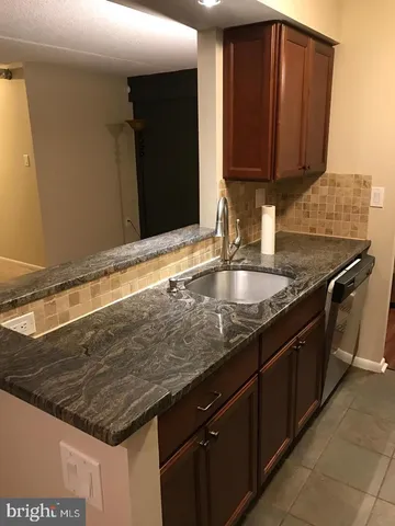 a kitchen with granite countertop a sink and a wooden cabinets
