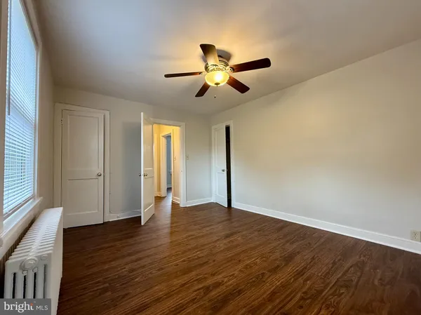 a view of empty room with wooden floor and fan