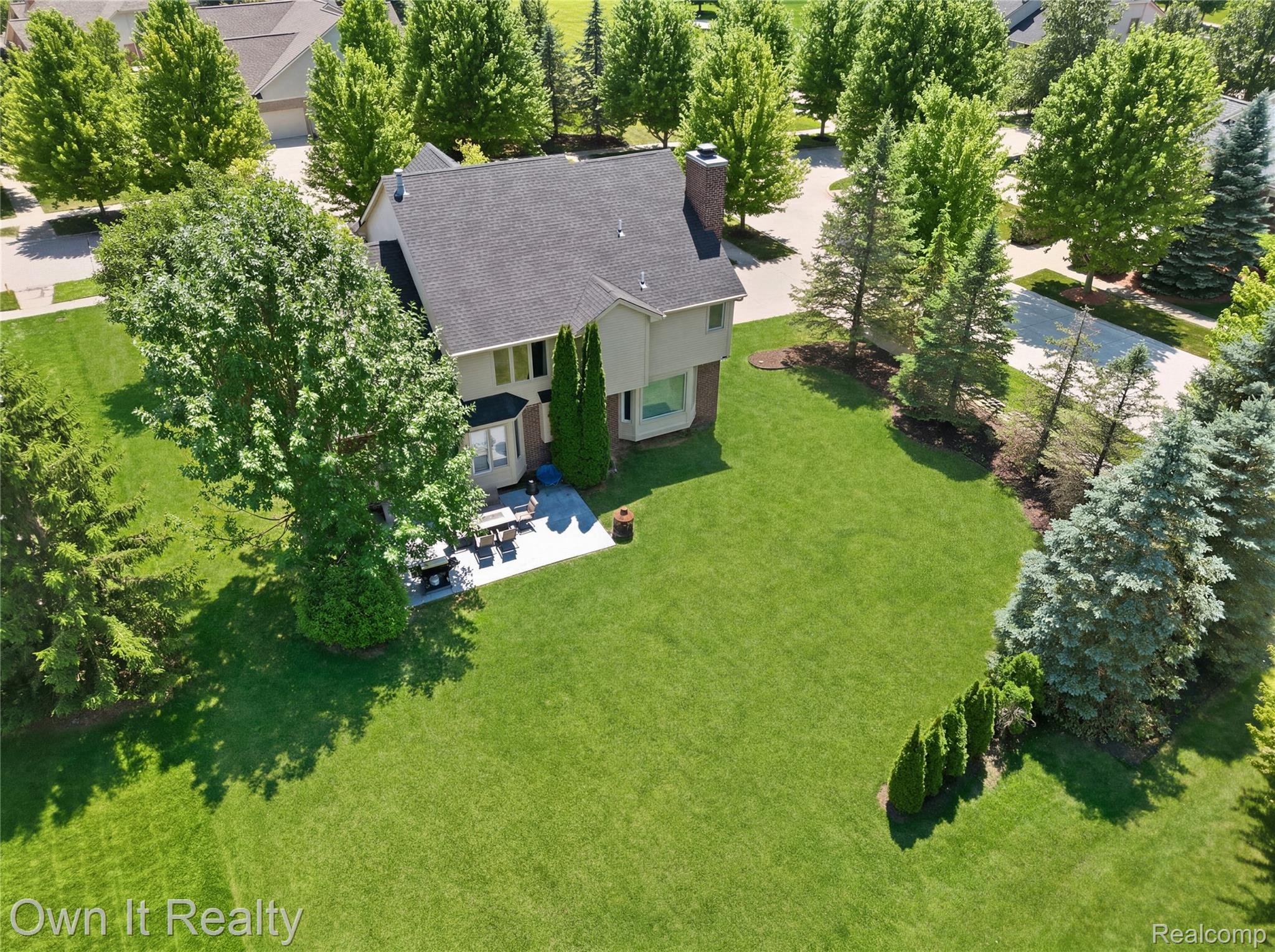 48280 Gladstone Road Canton, MI 48188 - Photo 4 of 59 Expansive green lawn with mature trees and a paved patio