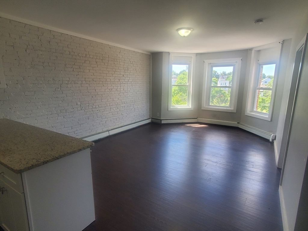 620 Dudley Street, Unit 4 Boston, MA 02125 - Photo 3 of 15 an empty room with wooden floor and windows