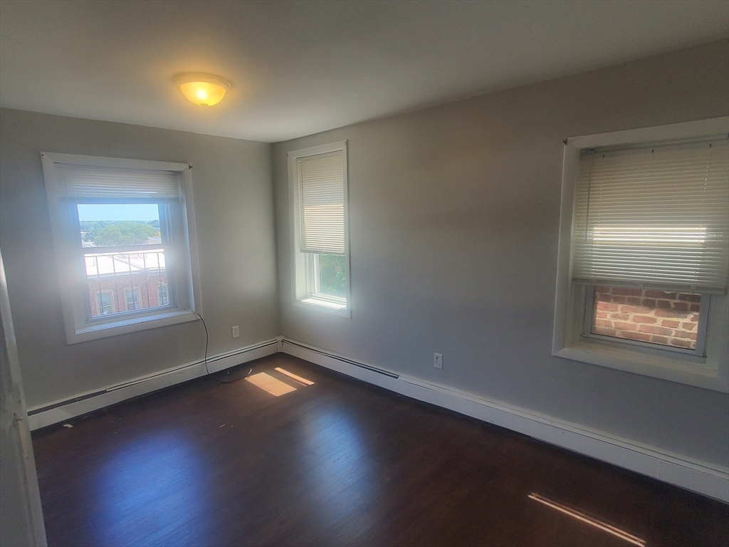 620 Dudley Street, Unit 4 Boston, MA 02125 - Photo 6 of 15 a view of an empty room with wooden floor and a window