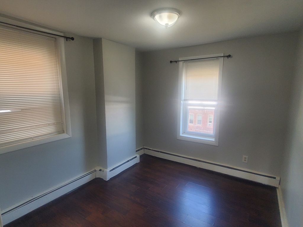 620 Dudley Street, Unit 4 Boston, MA 02125 - Photo 7 of 15 an empty room with wooden floor and windows