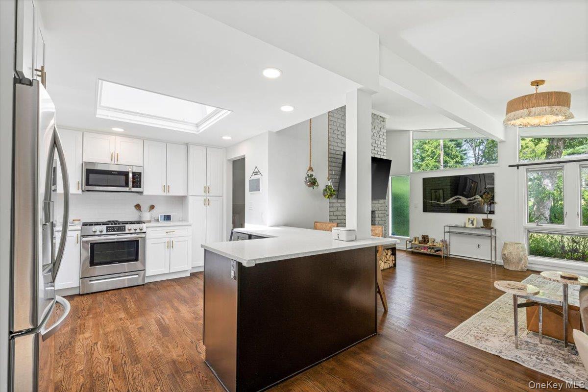 43 Winslow Road White Plains, NY 10606 - Photo 9 of 32 a open kitchen with stainless steel appliances a stove top oven a sink dishwasher a refrigerator white cabinets and wooden floor next to a window