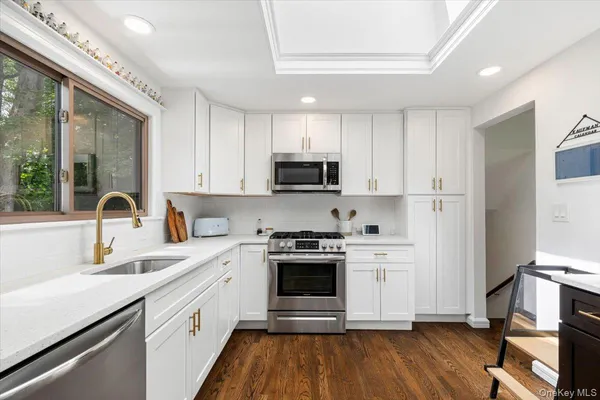 a kitchen with cabinets stainless steel appliances a sink and wooden floor