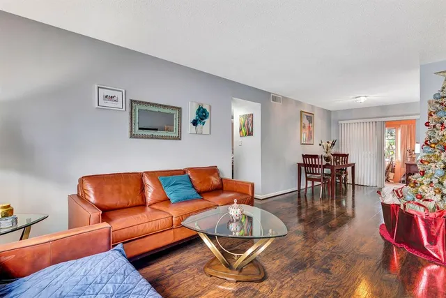 a living room with furniture and a dining table with wooden floor