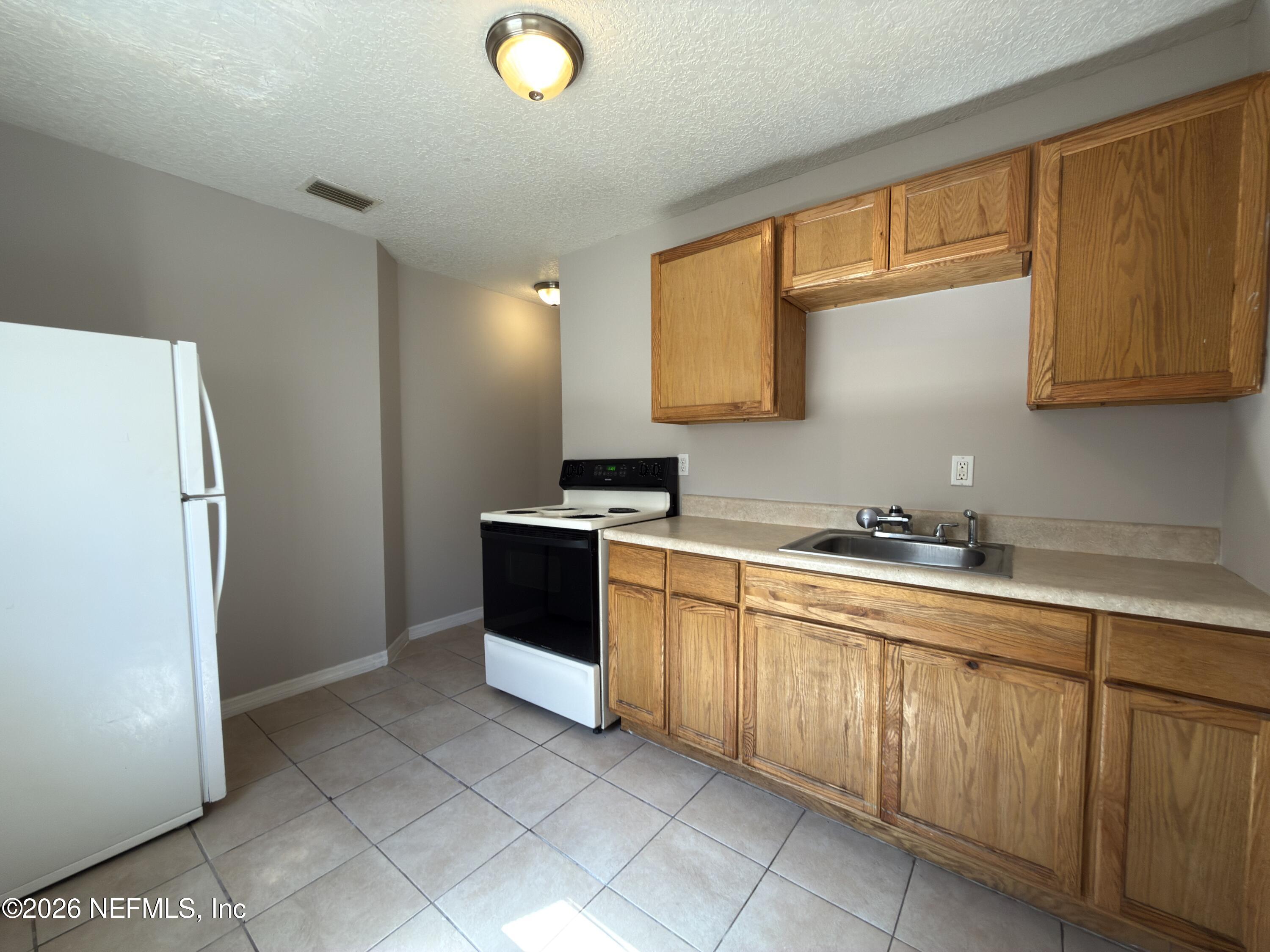 1709 Dot Street Jacksonville, FL 32209 - Photo 8 of 17 a kitchen with a sink a refrigerator and cabinets